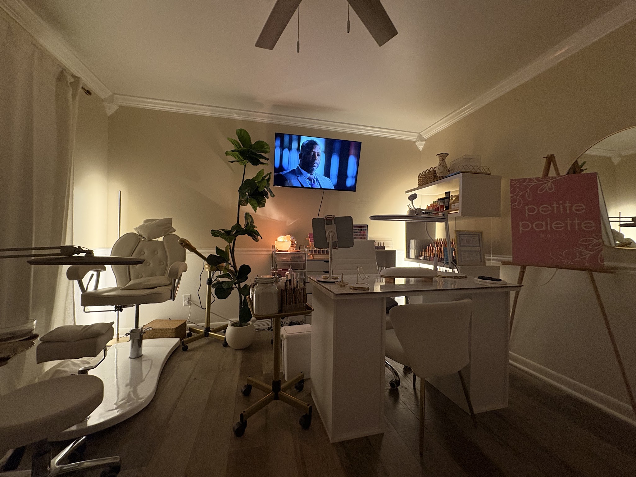 Inside the nail suite: manicure table, pedicure chair and a pink easel sign