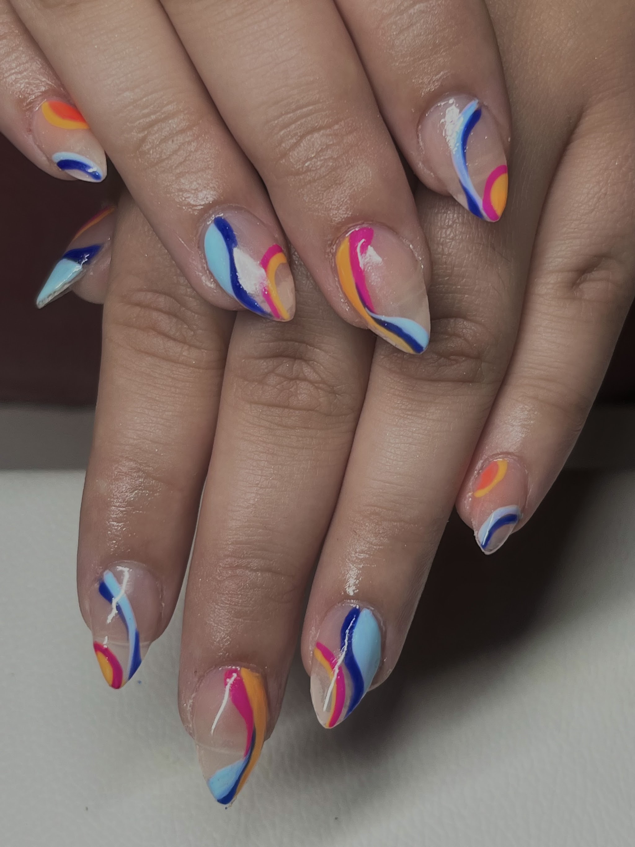 Hands with colorful swirl nail art in orange, blue and pink